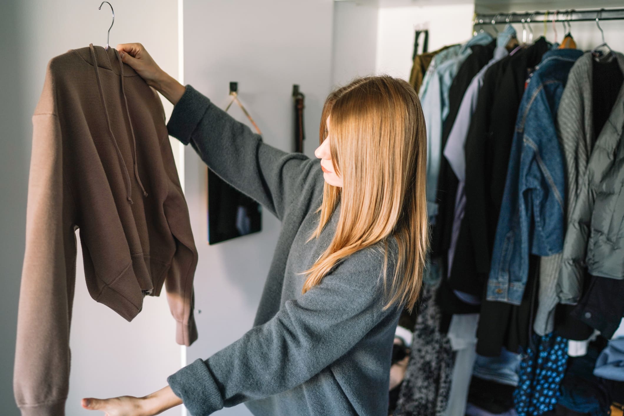 Una chica está cogiendo una sudadera y valorando qué hacer con ella.