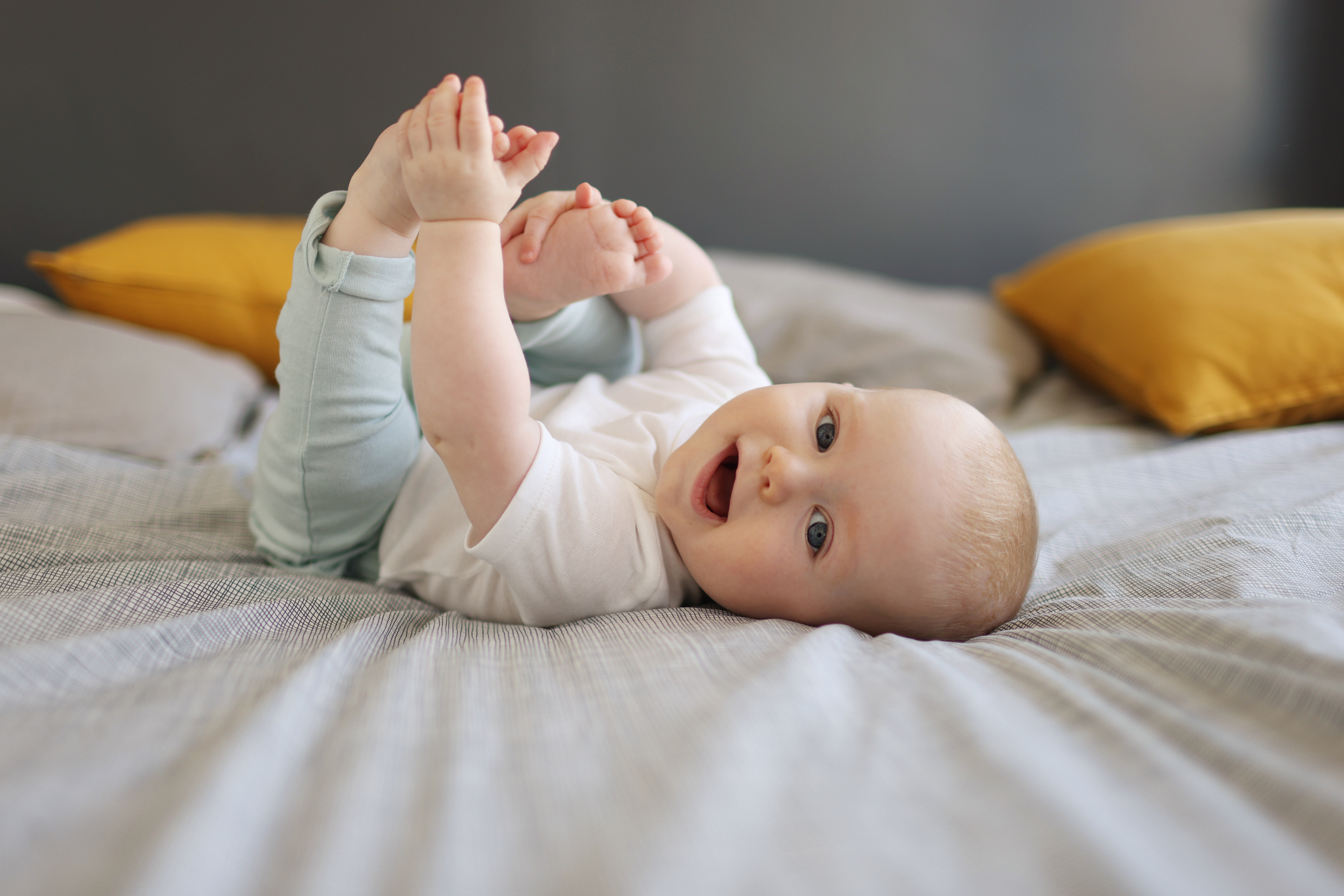 Un bebé sonriendo tumbado en la cama.
